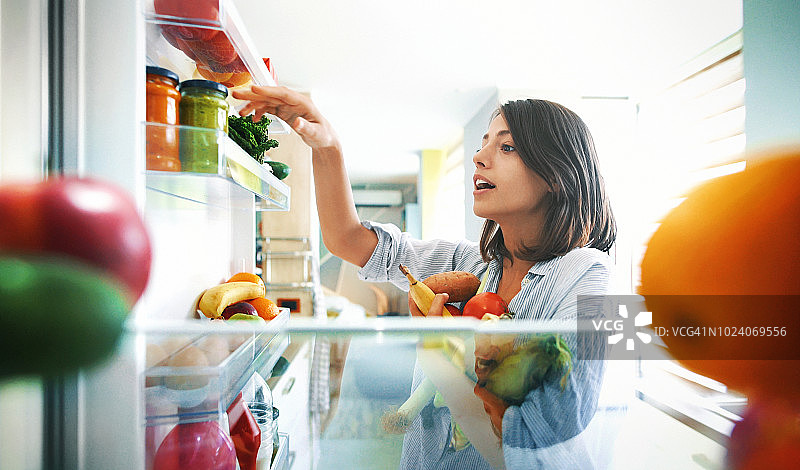 从冰箱里拿水果和蔬菜的女人图片素材