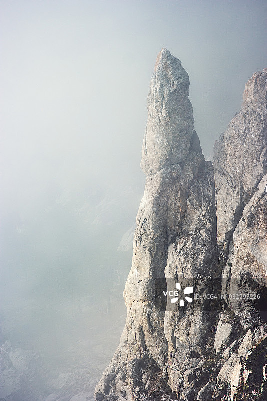 雾蒙蒙的岩石山悬崖景观极简主义风格旅游宁静的风景鸟瞰穆迪天气图片素材