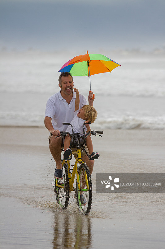 父亲和儿子在海滩上骑自行车图片素材