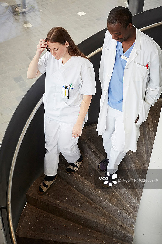 多民族医生在医院的螺旋楼梯上移动的高角度视图图片素材