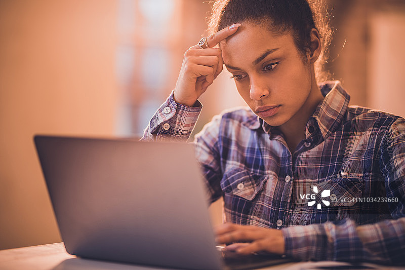 一位年轻的黑人女士在笔记本电脑上阅读一封有问题的电子邮件。图片素材