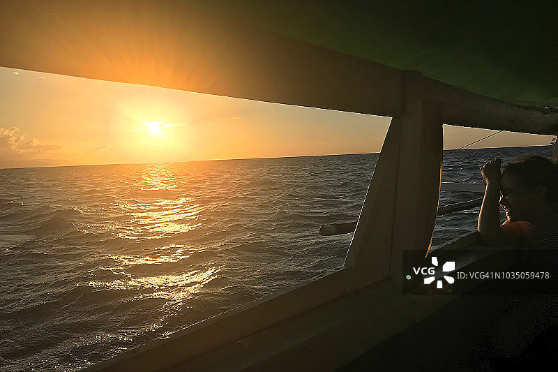 小女孩在帆船上欣赏日落。图片素材