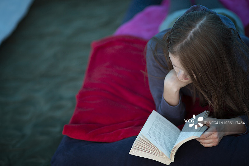 一个十几岁的女孩躺在帐篷里看书图片素材