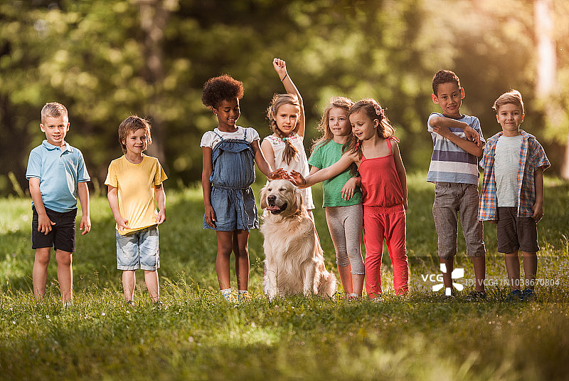 春天的一天，快乐的孩子们和金毛猎犬在公园里玩耍。图片素材
