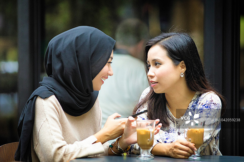 一名穆斯林女性在街边咖啡馆向她的朋友倾诉图片素材