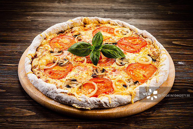 有火腿、番茄和蘑菇的披萨，背景是木头图片素材
