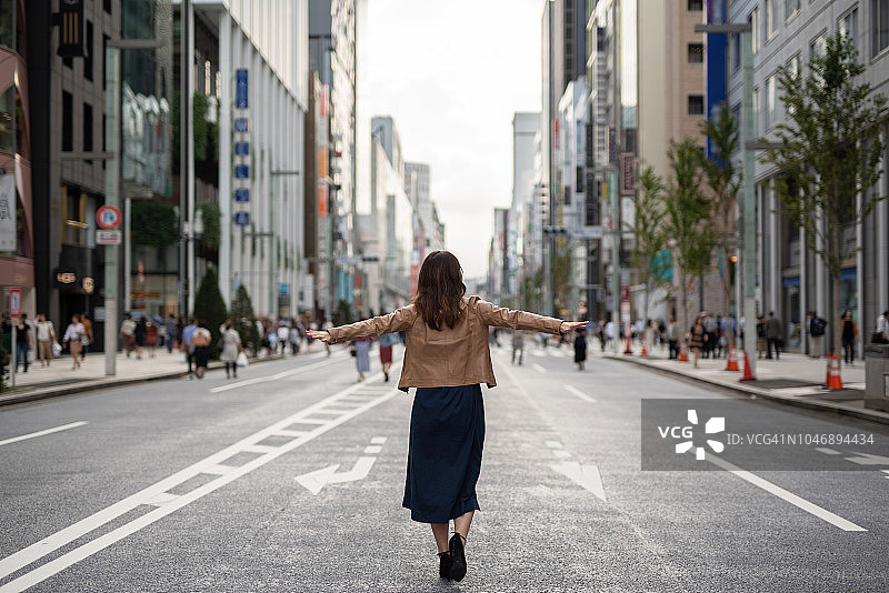 快乐的女人张开双臂走在街上图片素材