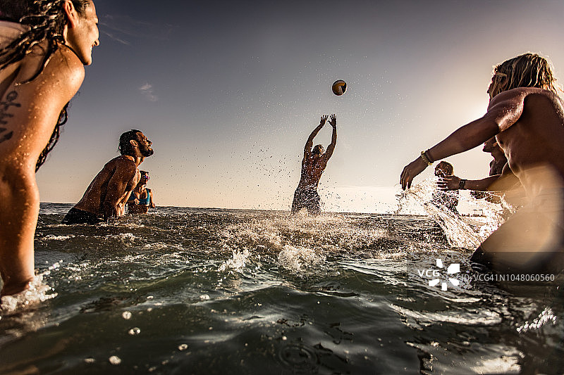 嬉戏的朋友们在海里玩排球，玩得很开心。图片素材