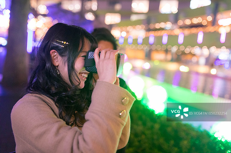一对青少年情侣在圣诞灯光下玩VR眼镜图片素材