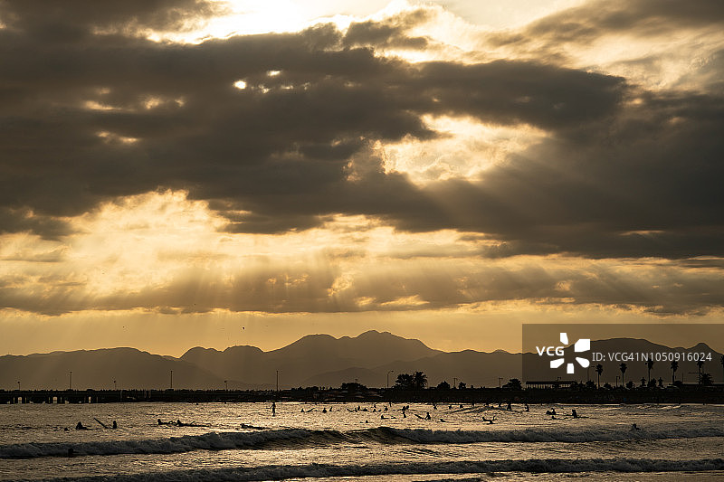 在日本神奈川县的相模湾和箱根山，许多冲浪者身上的橙色夕阳阳光图片素材