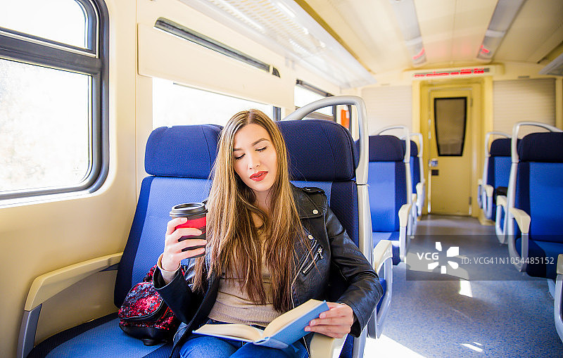 在火车上拿着书的女人。图片素材