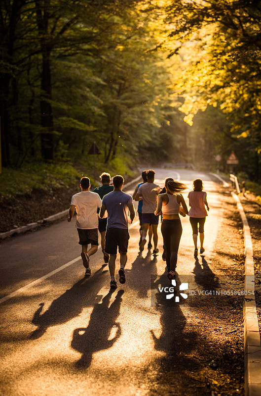 日落时分，一群人在柏油路上跑马拉松。图片素材