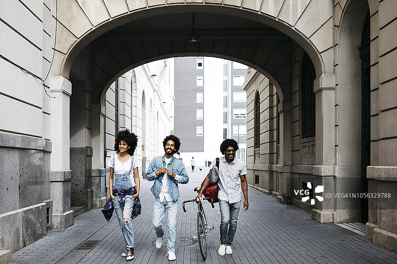 西班牙，巴塞罗那，三个朋友赛车自行车走在街上图片素材