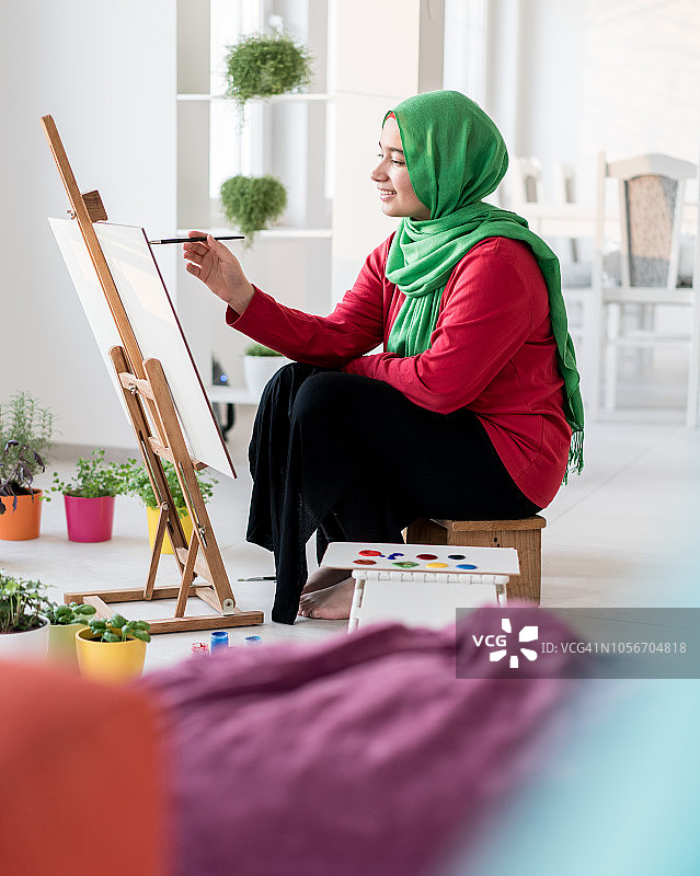 穆斯林女孩在家里的画架上作画图片素材