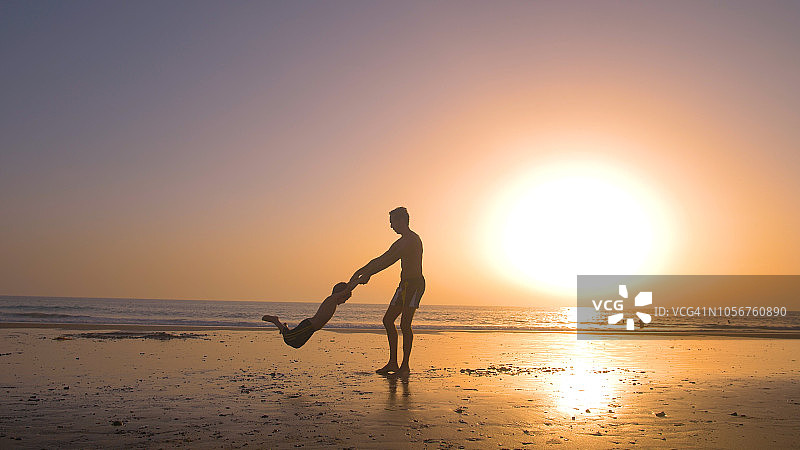 日落时分，海滩上父亲和两个孩子的剪影图片素材