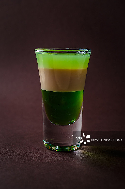 绿色酒精小酒杯，爱尔兰奶油，酒在优雅的深棕色背景图片素材