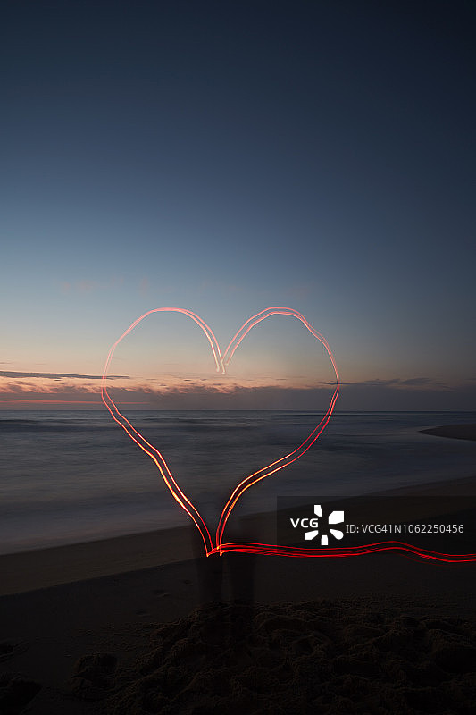 日落时海滩上心形的红外光迹(光绘)图片素材