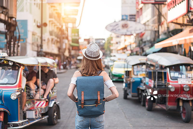 一名年轻女子的背影在泰国曼谷的步行街上走了又走，晚上游人如云。图片素材