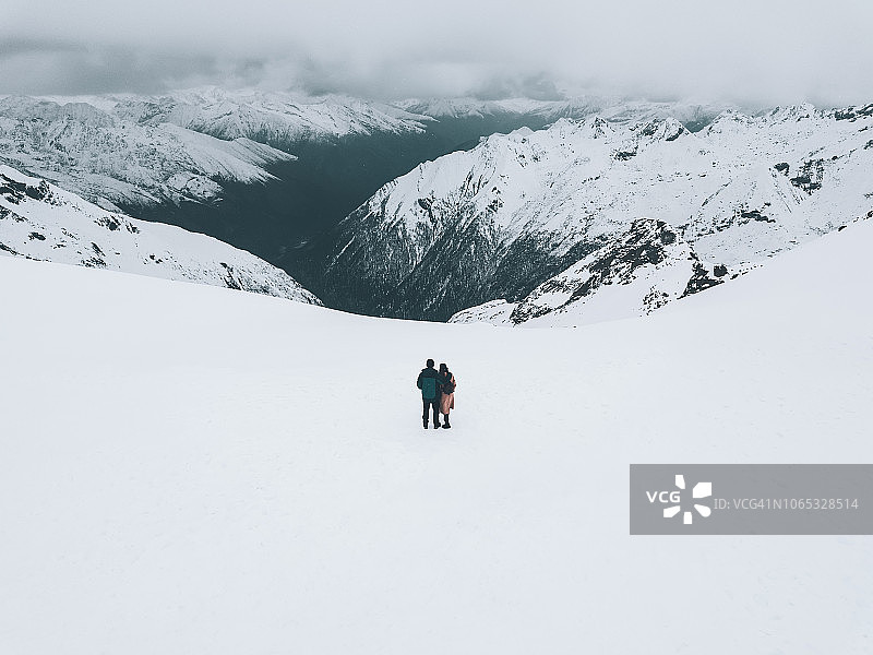 男性和女性徒步旅行者拥抱在雪山上，后视图图片素材