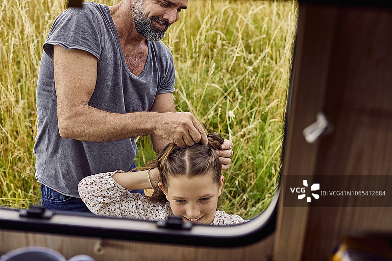 父亲在一辆大篷车旁给女儿编头发图片素材