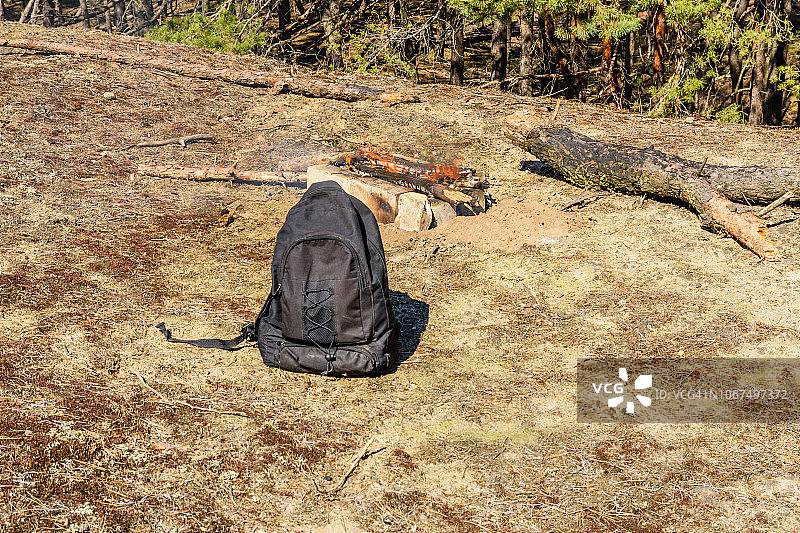 背包在针叶林的地面上。篝火的背景图片素材