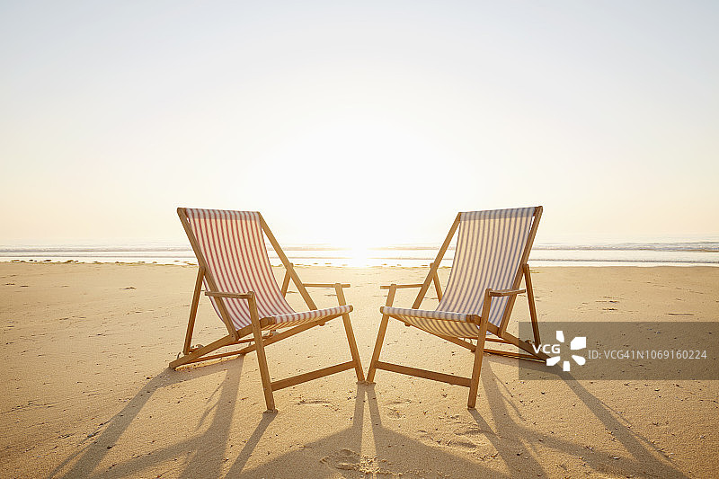 日落时分沙滩上的两把躺椅图片素材