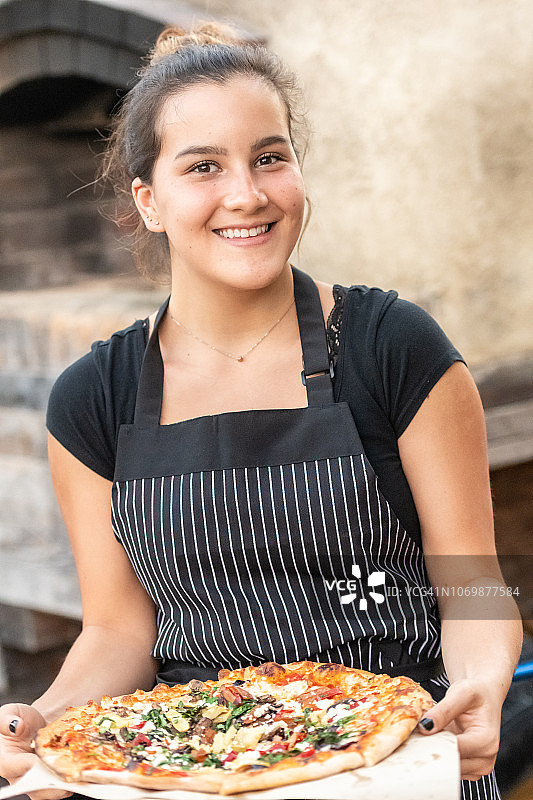 微笑的年轻女子在一个砖炉前摆姿势图片素材
