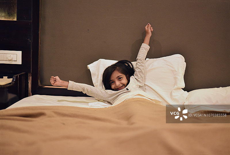 年轻的女孩在床上伸懒腰图片素材