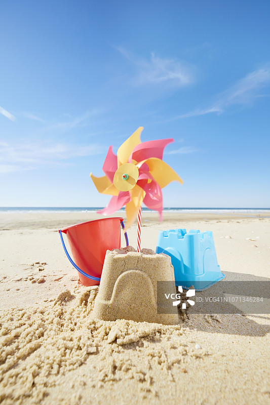 沙滩上的沙堡有五颜六色的沙玩具和移动风车图片素材