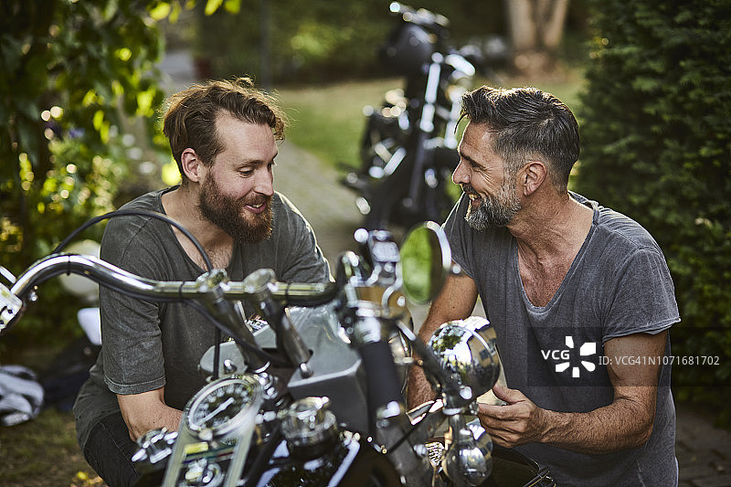 两个开心的男人骑着摩托车在花园里图片素材