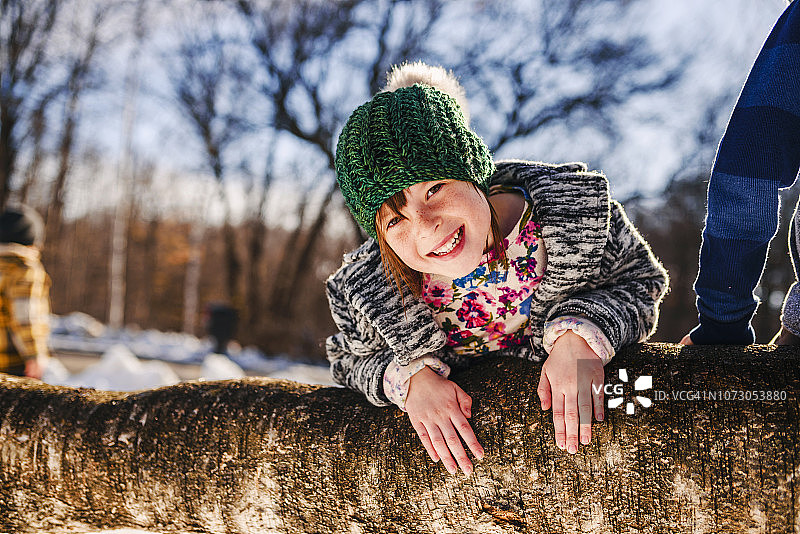 一个微笑的女孩爬树的肖像，美国图片素材