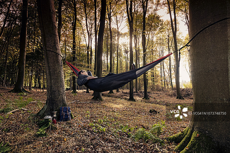 一个男人在树林里的吊床上休息图片素材