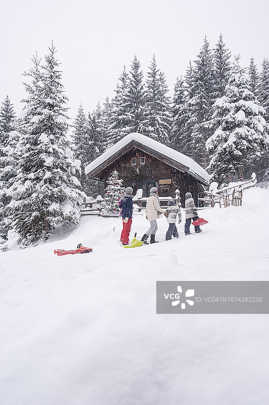 奥地利Altenmarkt-Zauchensee，一家人在木屋里拉着雪橇过圣诞节图片素材