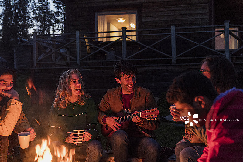 一群朋友围坐在篝火旁，一边聊天一边弹吉他图片素材