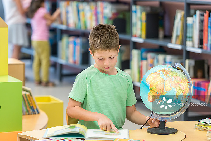 小男孩在图书馆看地球图片素材