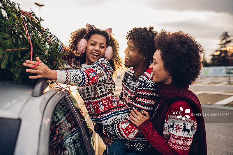 欢乐的一家人把圣诞树挂在车上图片素材