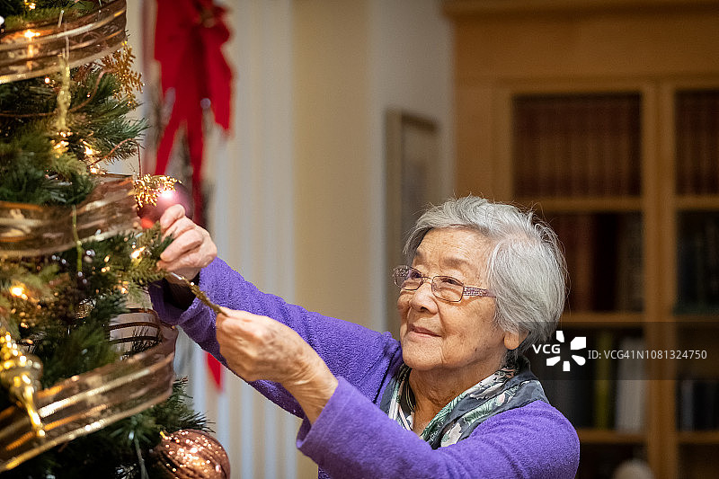 90岁的亚洲妇女在家里装饰圣诞树图片素材