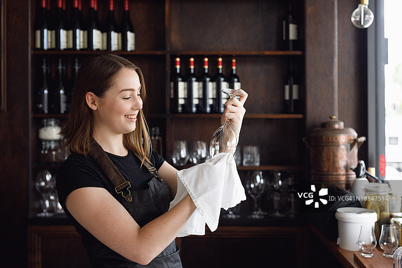 女服务员在凉爽的酒吧清洁酒杯图片素材