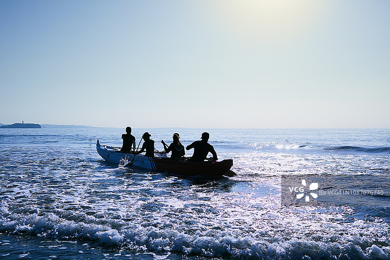 男男女女在太平洋上划着独木舟。图片素材