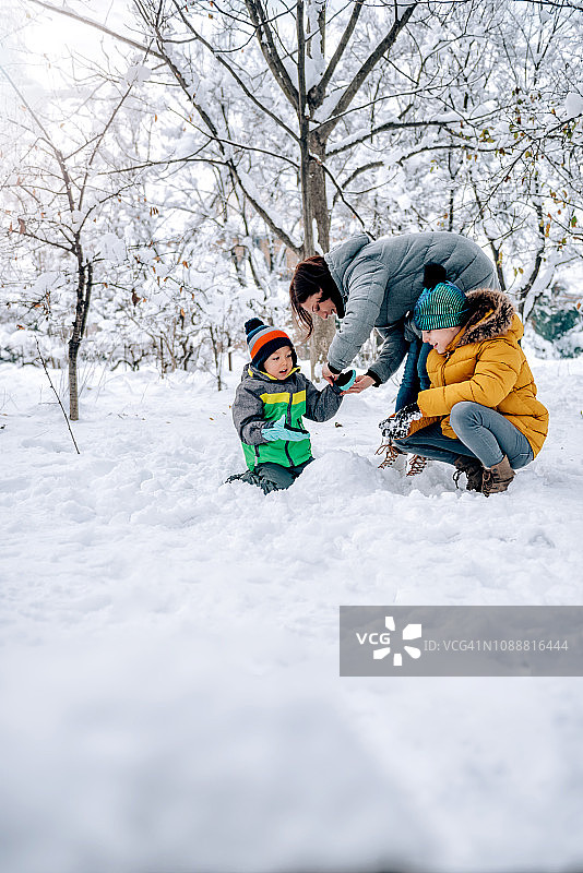 妈妈帮儿子戴上雪地手套图片素材