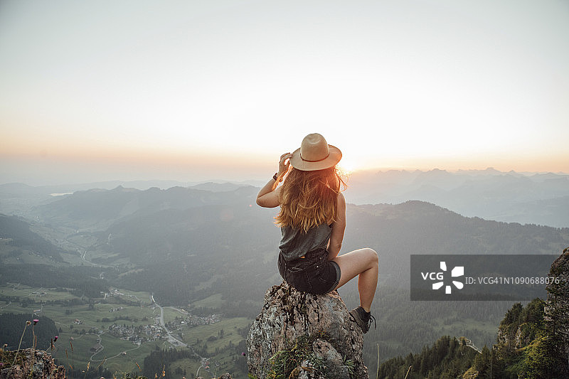 瑞士，格罗瑟·麦森，一名徒步旅行的年轻女子，日出时坐在岩石上图片素材