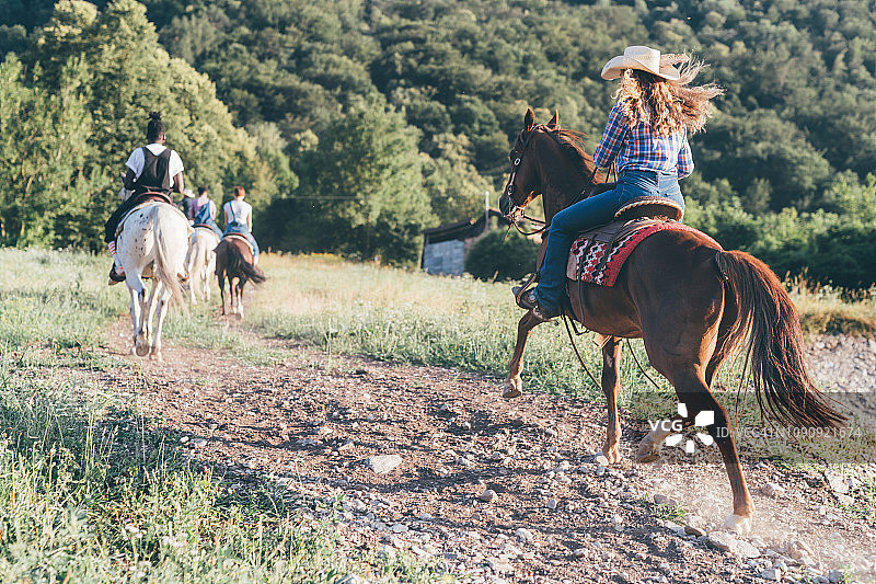 年轻人骑马在乡村景观，后视图，Primaluna，特伦蒂诺-上阿迪杰，意大利图片素材