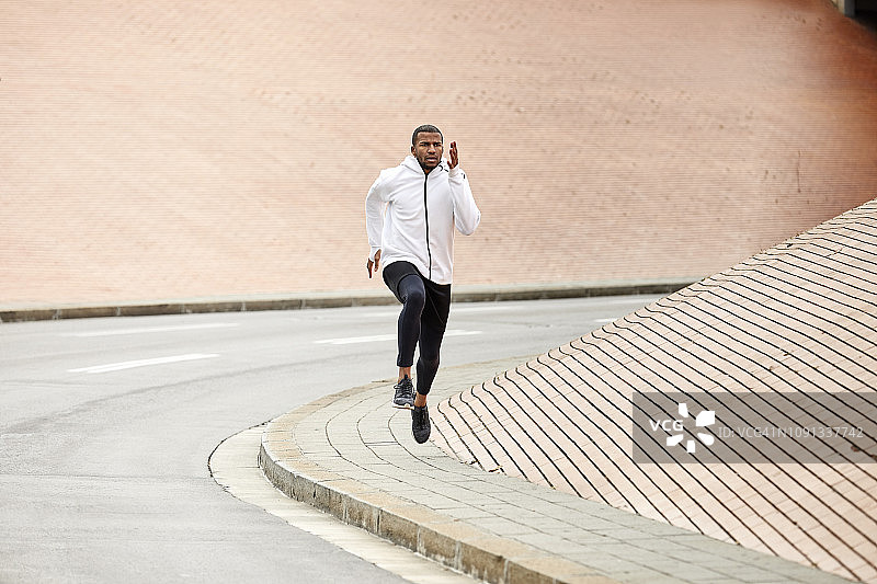 运动男性在路边靠墙慢跑图片素材