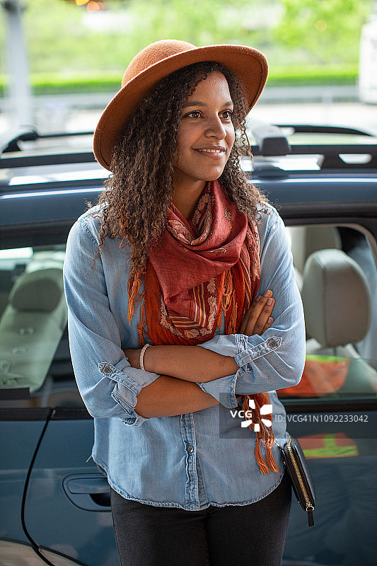 时髦的年轻混合种族妇女等待汽车在机场接和落区。图片素材