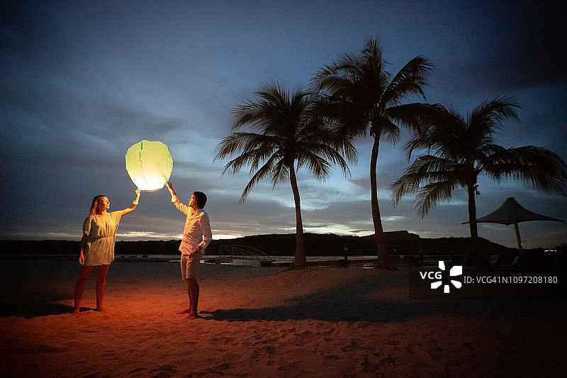 日落时分，一对夫妇在海滩上提着灯笼图片素材