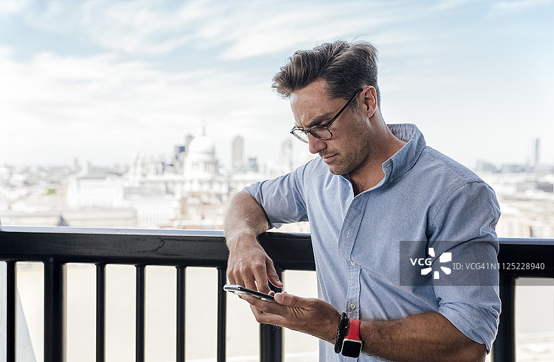 英国，伦敦，一名男子在屋顶露台上使用手机图片素材