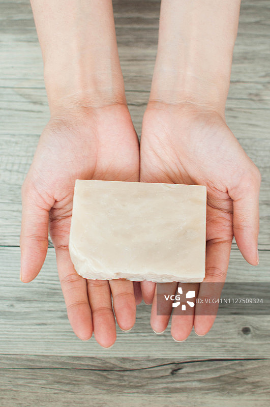 一个女人的手拿着白色有机肥皂的特写图片素材