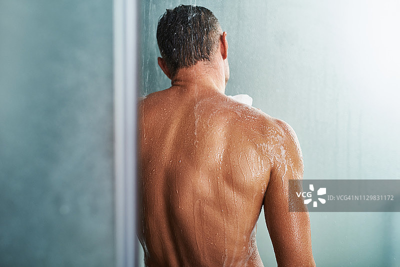 英俊的年轻人站在水珠下洗澡图片素材
