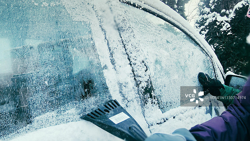 女司机刮着白雪覆盖的车窗图片素材