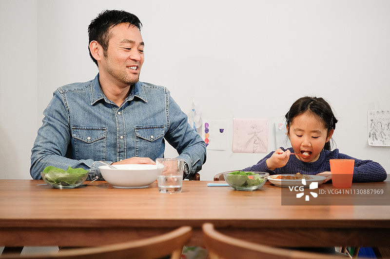父亲和女儿在家里一起吃咖喱饭图片素材